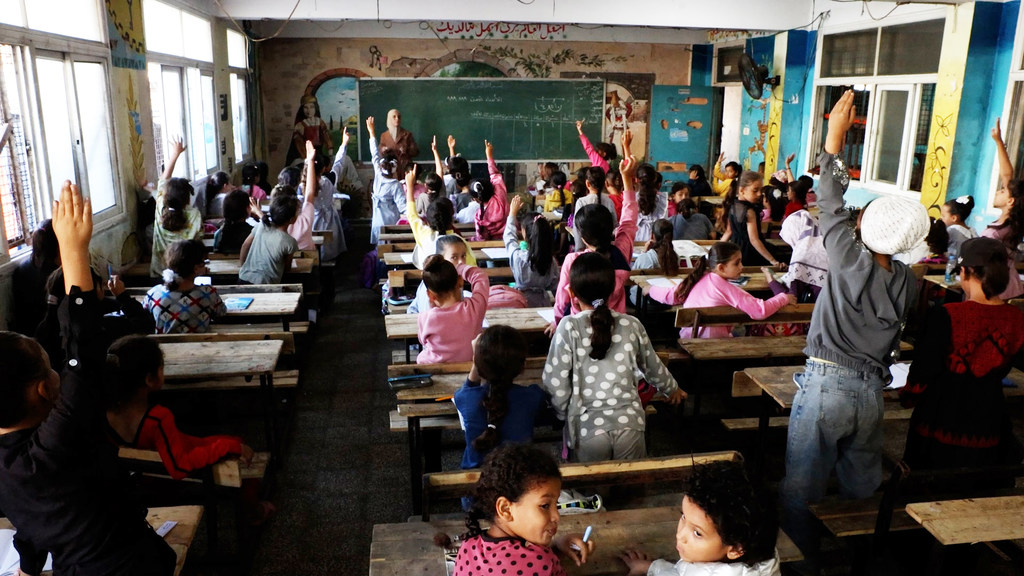 طالبات يتفاعلن مع مدرستهن في أحد الفصول الدراسية في مدرسة دير البلح الابتدائية المشتركة في غزة، التي تديرها وكالة الأونروا.